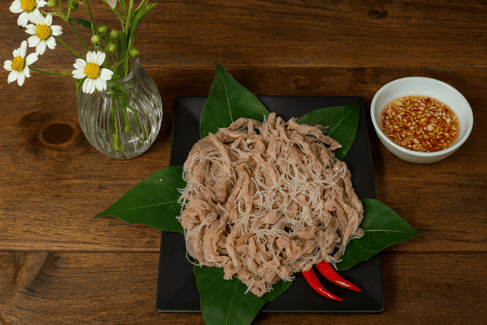 Nem Chua Yen Mac is a tangy, mildly spicy fermented pork roll wrapped in fragrant banana leaves, offering a chewy texture and distinctive northern flavor
